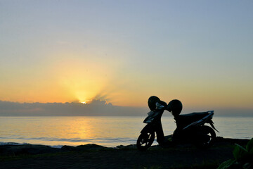 Fototapeta na wymiar Silhouette scooter parked at seaside of Matahari Beach during sunrise.