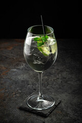 Hugo cocktail with Prosecco, lime, ice, mint and Melissa syrup on a stone background, aperitif drink