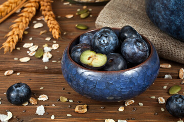 Blueberries in a blue ceramic cup with wheat ears on a wooden background.