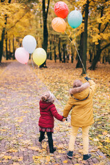 brother and sister playing with balloons in an autumn park