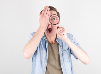 Shocked man looking through a magnifying glass © MP Studio