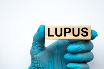 The doctor's hands show the word LUPUS . a gloved hand on a white background. Medical concept. the medicine