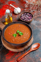 Vertical view of tomato soup on a brown cutting board and beans on a mixed color table