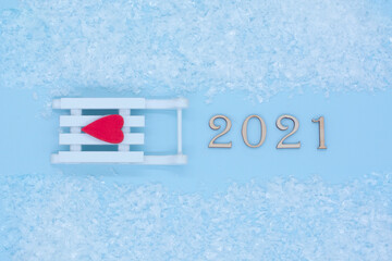 Symbol from number 2021 and white sled with a red heart on a blue background .New year and merry Christmas concept.