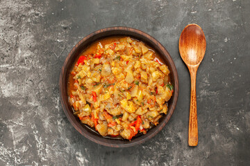 top view roasted eggplant salad in bowl wooden spoon on dark background