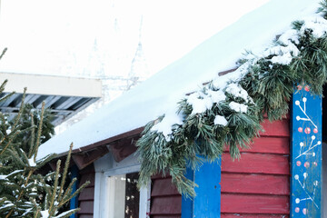 Snow-covered roof decorated with fir branches, close-up