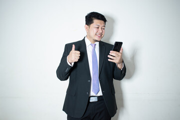 
Portrait of a smiling businessman dressed in suit purple necktie is working on mobile phone in white background.