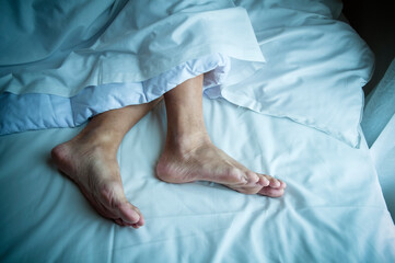 Exposed feet of adult male lying in bed