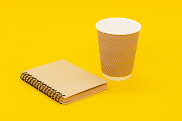 coffee cup and craft notebook on a yellow background.