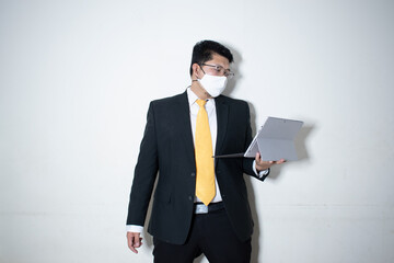 Young asian business man in face mask using laptop computer isolated on white background, quarantine and epidemic covid-19, businessman work from home for health, social distancing, new normal.