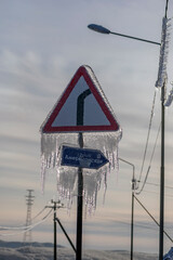 Ice rain series: road sign covered with ice on a blue sky background
