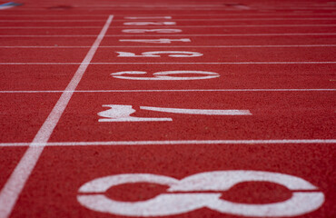 White numbers on starting line of a running track field, 1-8, with straight white lines divided...