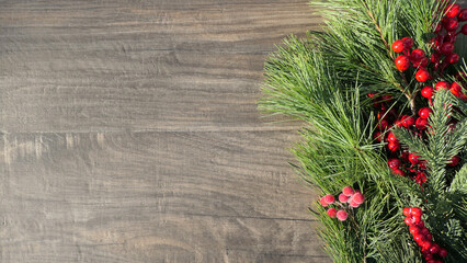 christmas tree branches and red berries on wooden background - copy space