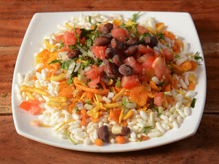 Bhel puri, a famous midday snack in india, served over a rustic wooden background, selective focus