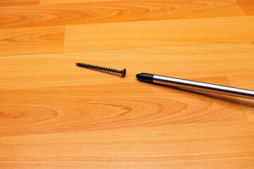 self-tapping screw and screwdriver on wooden background