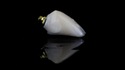 beautiful dental crown made of ceramic with water drops on black glass