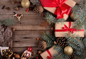 Gift box with red silk bow among Christmas decorations on a wooden table. Merry Christmas and Happy New Year background with copy space for text.