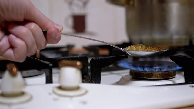 Hand Male Addict Cooks Heroin in Spoon Over Gas Stove at Home