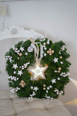 Christmas wreath made of 
spruce branches together with a lighting star. Interior decoration for christmas time.
