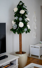 Christmas tree on the the natural pine trunk with white decorations. Interior decor.
