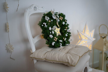 Christmas wreath made of 
spruce branches together with a lighting star. Interior decoration for christmas time.
