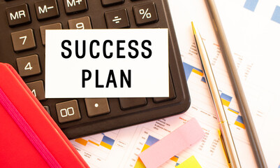 Text SUCCESS PLAN on white card with metal pen, calculator and financial charts.