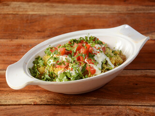 Dahi aloo chaat is a special dish in India. The dish is eaten as a midday snack, served over a rustic wooden background, selective focus