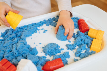 Close view of child's hands playing with kinetic sand. Children's creative game for early...