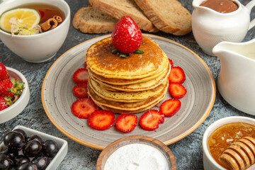 front view yummy pancakes with tea and fruits on the light background fruit cake sweet