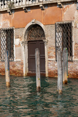 Venice, Italy. Close up of a waterfront building with wooden portal or door partly submerged by the water. Water at very high level submerging steps and doorways and almost touching the windows.