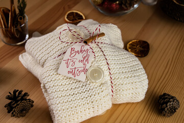 Wed woolen sweater wrapped as a gift, surrounded with dry orange slice and pinecone