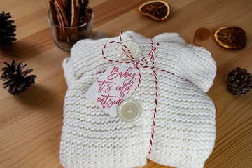 White woolen sweater wrapped as a gift, surrounded with dry orange slice and pinecone