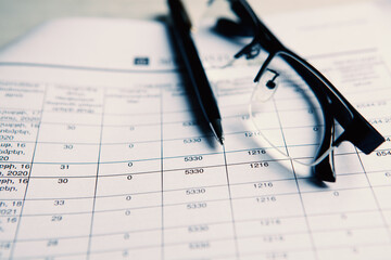 glasses with pen close up and financial report - accounting concept