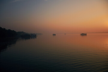 Naklejka premium A winter morning at Sundarbans river delta in West Bengal, India. Few tourist motorboats are seen moored in middle of river water during sunrise.