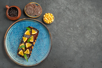 Above view of delicious cakes on blue tray and biscuits on dark background
