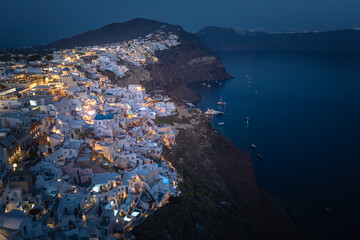 Oia town on Thira. Santorini island with colorful volcanic cliffs and deep blue sea aerial view