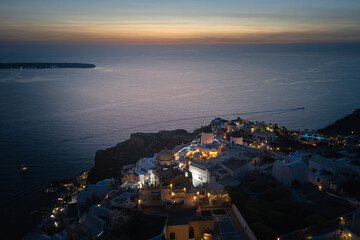 Oia town on Thira. Santorini island with colorful volcanic cliffs and deep blue sea aerial view