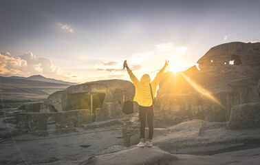 Woman stands on rock in historical place with spreaded hands out of joy. Travel and freedom of travel.
