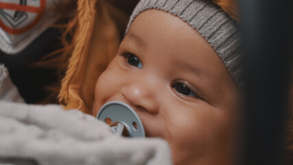 Portrait of adorable baby in car seet with pacifier and hat smiling. High quality photo
