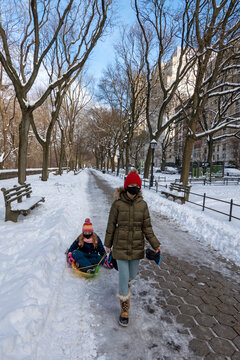New York, USA, December 2020.  Young girls wearing masks with their sled on the Upper West Side, Manhattan, NYC during the Covid crisis.