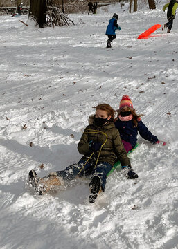 New York, USA. December 2020. Two young girls sleding on snow at Riverside Park in Manhattan, NYC
