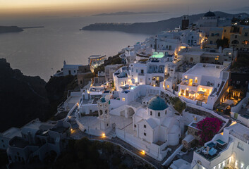 Oia town on Thira. Santorini island with colorful volcanic cliffs and deep blue sea aerial view