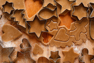Cutting different shapes of Christmas gingerbread cookies from the dough, close up view