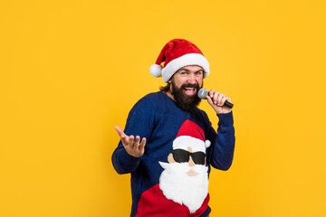 bearded santa man singing in microphone in hat smiling while prepare for celebrating happy new year party and christmas holiday in winter going to have xmas presents, xmas singer