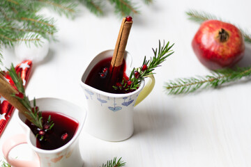 christmas mulled wine in heart shaped cups, cinnamon, rosemary, garnet, fir tree branches, santa hat, new year decoration on white background