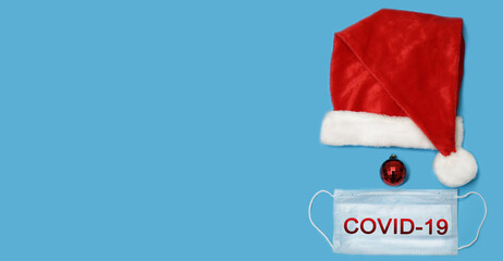 Santa Claus hat on a blue background. Mockup for design creation. Festive Christmas quarantine. Celebrating Christmas in the Covid-19 period. For wallpapers, cards and backgrounds.