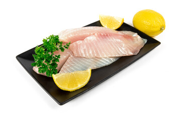 Tilapia fish filets on a modern black plate with lemon and parsley isolated on white