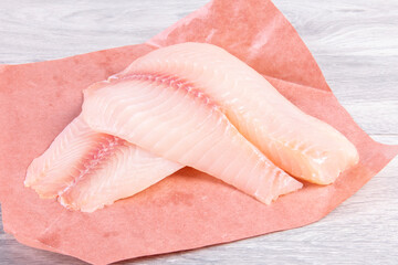 Two fresh raw Tilapia fish filets on brown wrapping paper
