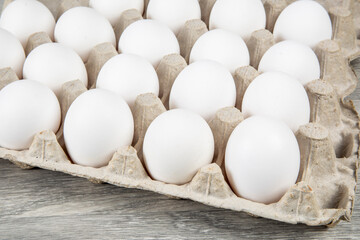 A dozen white eggs in the corner of a 30 egg carton
