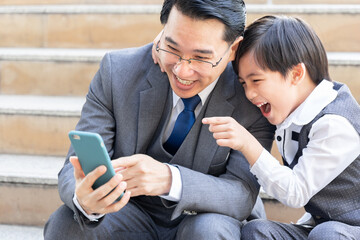 Father and son playing  smart phone together on business district urban, Dad and Son happy Asian family concept